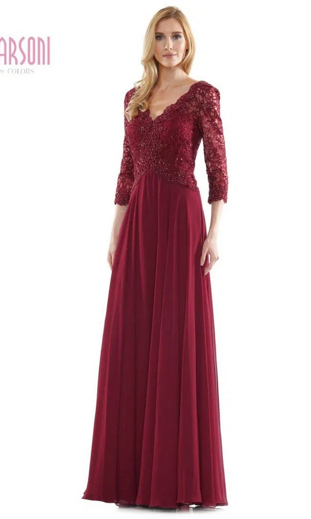 A woman stands wearing the Marsoni M225 long formal dress in wine, featuring a lace-embroidered bodice, lace sleeves, and a V-neckline.